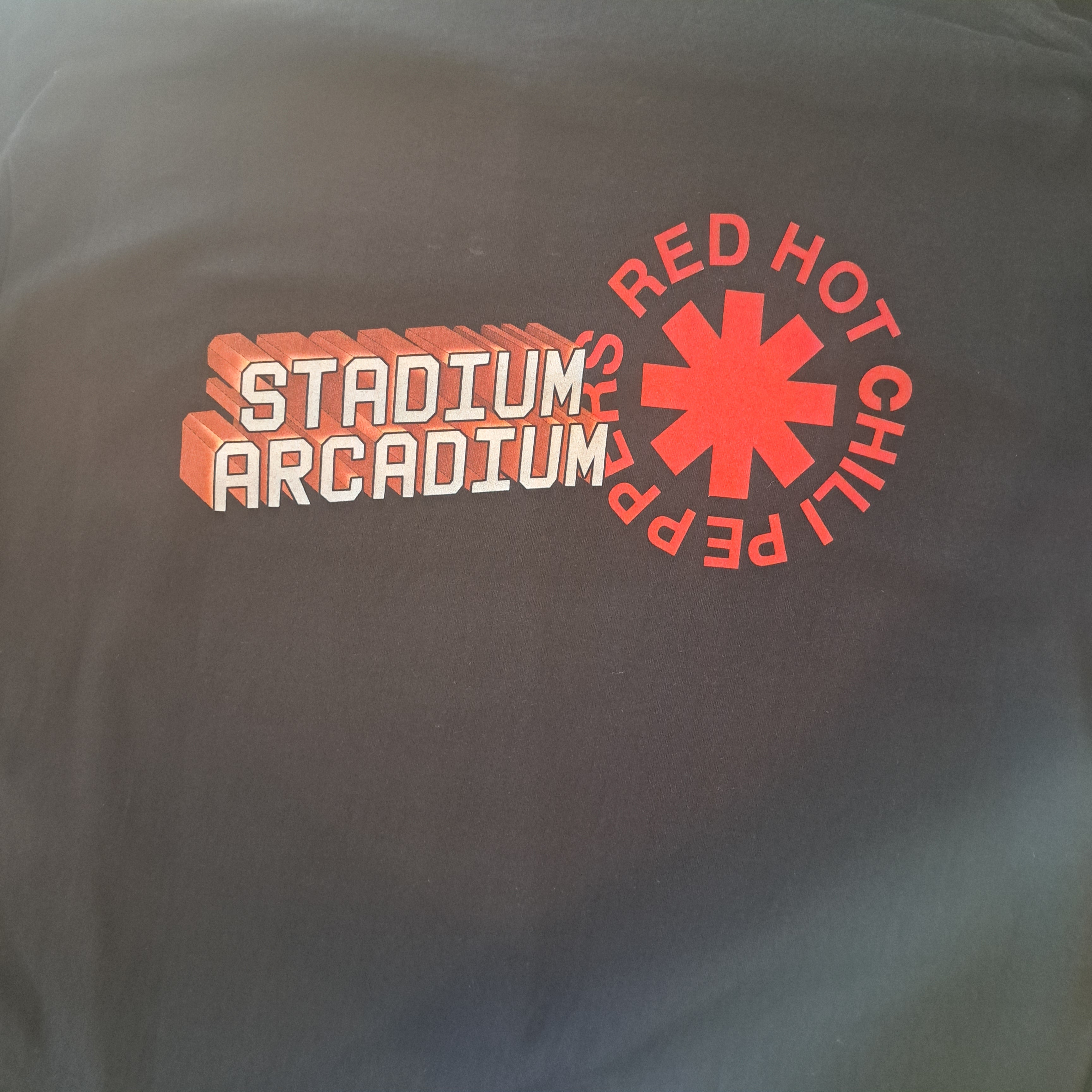 Gray t-shirt with Red Hot Chili Peppers logo and text on a plain background